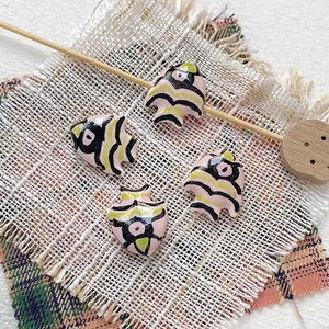 Detailed view of four handmade ceramic tropical fish beads on rustic linen background