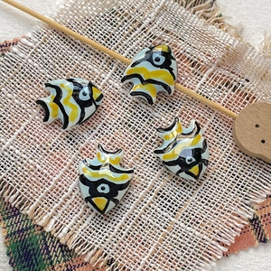 Detail of four hand-painted tropical fish ceramic beads with yellow and black stripes