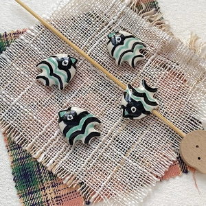 Macro detail of hand-painted ceramic tropical fish beads for DIY jewelry making