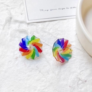 Detailed view of colorful rainbow umbrella stud earrings with gold plating on white surface