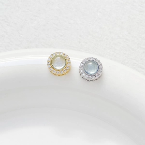 Detailed view of round gold and silver charms with inset blue stones and zircon stones