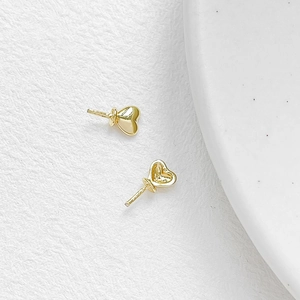 Macro shot of gold-plated heart-shaped jewelry pins with smooth metallic texture for DIY