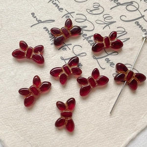 Detailed view of red glass butterfly beads with gold edges for DIY jewelry making