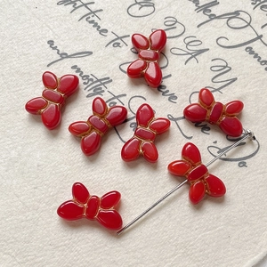 Detailed macro view of red butterfly beads with gold trim for DIY jewelry making