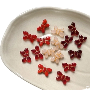 Vintage red butterfly glass beads for DIY jewelry making in a ceramic dish