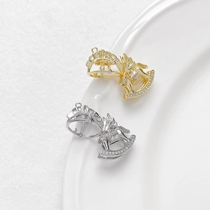 Zircon-studded rocking horse pendant in gold and silver plating shown on ceramic tray