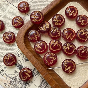 Detail of red Czech glass bird beads with gold engraving for DIY jewelry making