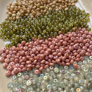 Macro detail of Czech glass spacer beads in olive green, dusty rose, and iridescent blue