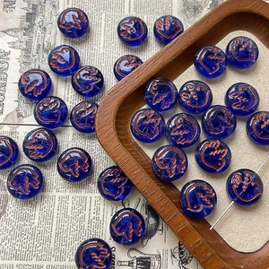 Macro detail of 10mm dark blue Czech glass beads with hand-painted gold dove patterns