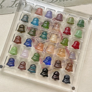 Colorful bell-shaped glass beads for Christmas DIY jewelry making in a display tray