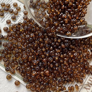 Macro shot of dark brown translucent glass seed beads scattered on vintage newspaper