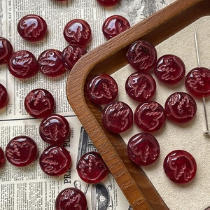 Macro view of vintage dark red Czech glass beads with embossed bird motif for DIY jewelry