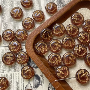 Close-up of brown Czech glass beads with gold painted bird patterns for jewelry making