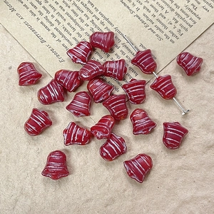 Detail of red Christmas bell glass beads on vintage paper for DIY jewelry making