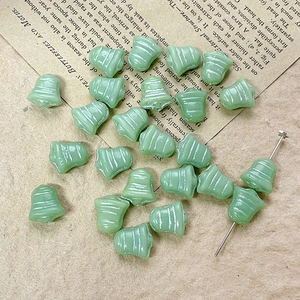 Detailed view of mint green bell-shaped Czech glass beads for DIY jewelry making