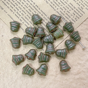 Macro shot of bell-shaped glass beads with copper etching on vintage script paper