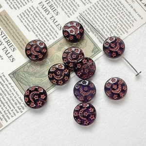 Close-up of deep purple Czech glass beads with vintage bronze moon and star patterns