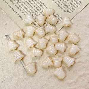 Macro view of bell-shaped cream Czech glass beads with golden stripes for DIY jewelry