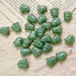 Detailed close-up of green bell-shaped Czech glass beads with vintage gold groove texture