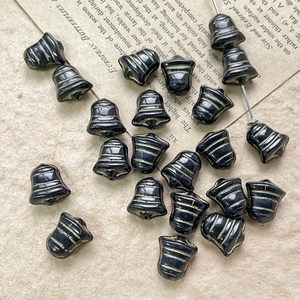 Close-up of vintage black bell-shaped glass beads with gold stripes on old book paper