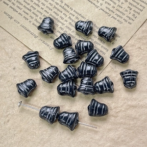 Close-up of black bell-shaped glass beads with silver ridges for DIY jewelry crafting