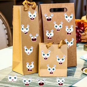 Cartoon rabbit and monster face stickers applied to kraft paper bags for Easter decor