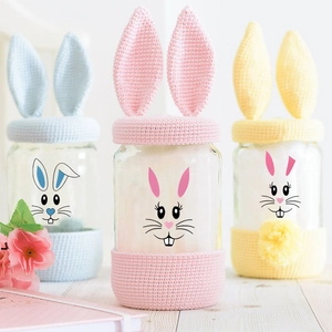 Three colorful Easter rabbit glass jars with knitted bunny ear covers and base sleeves
