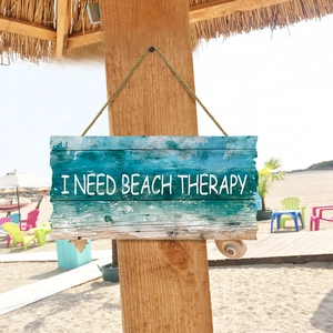 Wooden beach therapy sign with ocean waves design hanging on a beach umbrella pole