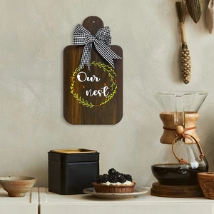 Rustic wooden kitchen wall plaque with Our Nest text and a black buffalo plaid bow decoration