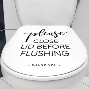 Close-up of black 'Please Close Lid' text sticker applied on a white toilet lid