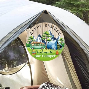 Rustic round wooden camper sign with summer motifs hanging on an outdoor tent