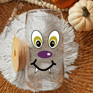 Halloween pumpkin ghost face decal on transparent glass cup with festive decor