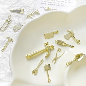 Detailweergave van mini gouden gereedschapshangers voor DIY sieraden op keramisch bord