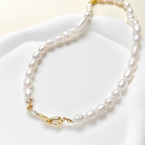 Baroque pearl necklace with 14k gold-plated heart-shaped zircon clasp on a white tray