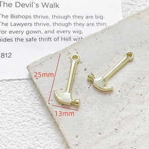 Detail van 25mm gouden klauwhamer hanger voor DIY-sieraden op witte stenen ondergrond
