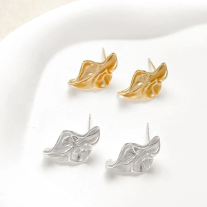 Nahaufnahme unregelmäßiger Barock-Ohrstecker in Gold und Silber mit metallischer Textur