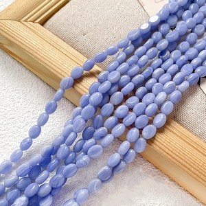 Détail de perles d'agate ovales bleu clair avec veines naturelles sur tissu de lin
