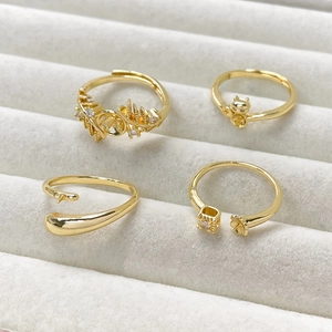 Dettaglio di anelli regolabili placcati in oro 14k con motivi di gatti e fiori in un cofanetto