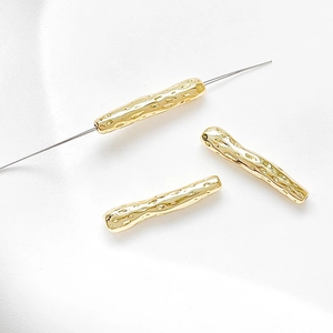 Macro shot of 14k gold-filled irregular long tube beads with hammered texture for DIY jewelry