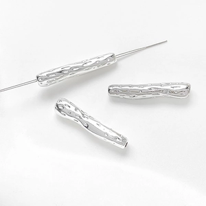 Macro detail of silver irregular textured twig tube spacer beads with center hole