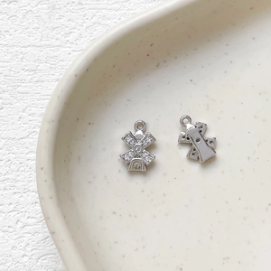 Detailed close-up of pair of windmill pendants with white zircons in 14k gold plated copper