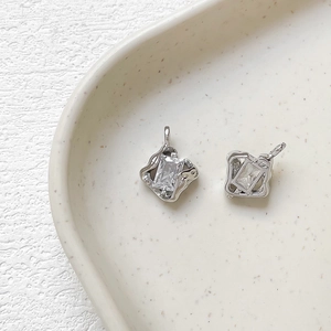 Detail of two silver irregular wave pendants with rectangular zircon in a ceramic tray