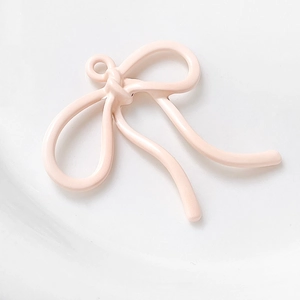 Gedetailleerd beeld van een lichtroze snoepkleurige strikhanger met oogje voor DIY-sieraden