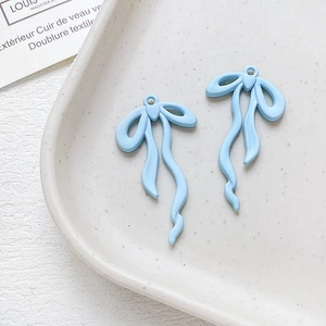 Dettaglio macro di ciondoli a fiocco azzurro con anellini per creazione gioielli