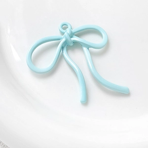 Macro-opname van lichtblauwe emaille strik hanger voor DIY sieraden maken op wit dienblad