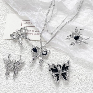 Macro detail of silver butterfly pendant charms with black resin and crystals