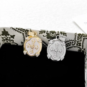 Detalle macro del colgante de cruz chapado en oro 14k con nácar y circonitas