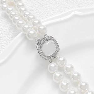 Double-layer white pearl necklace with a square cubic zirconia clasp on ceramic tray