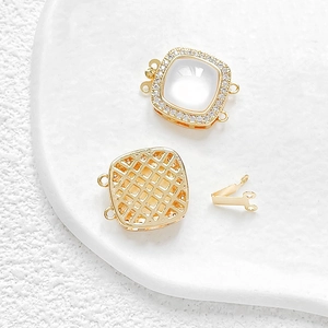 Macro detail of 14k gold plated square connector with white shell and pavé zircon stones