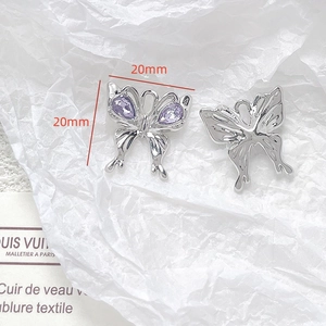 Macro view of 20mm silver butterfly charms with purple crystal teardrop inlays
